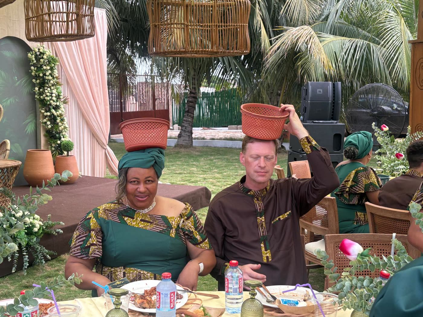 A host in traditional dress sharing a meal with volunteers
