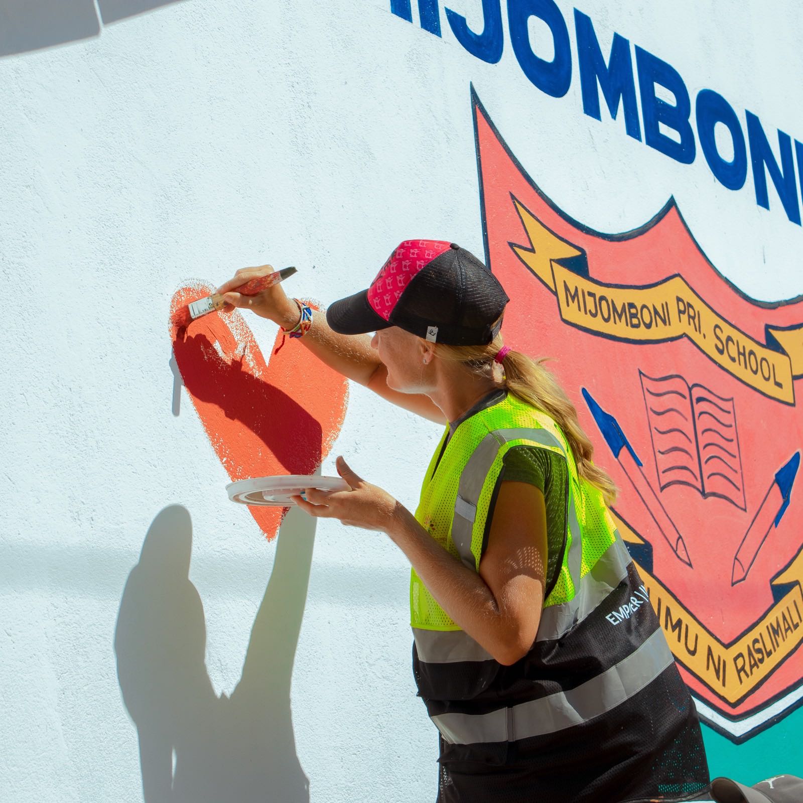 A volunteer painting the Mijomboni School crest