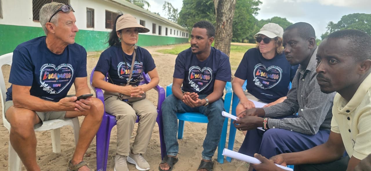 Volunteers in Dreamers shirts listening to local partners during a meeting