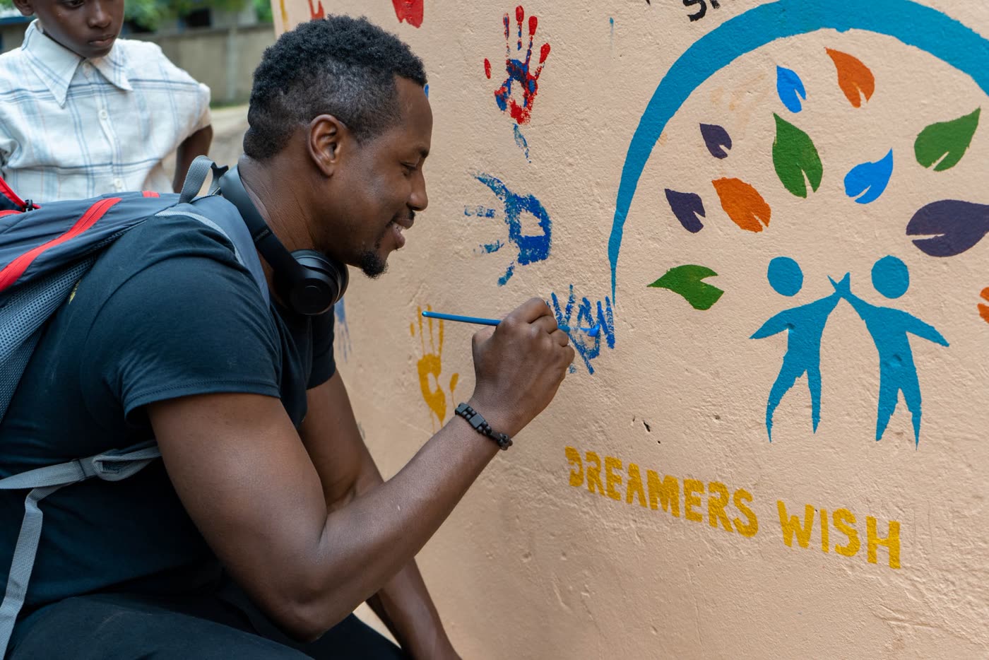 A volunteer painting a Dreamers Wish mural