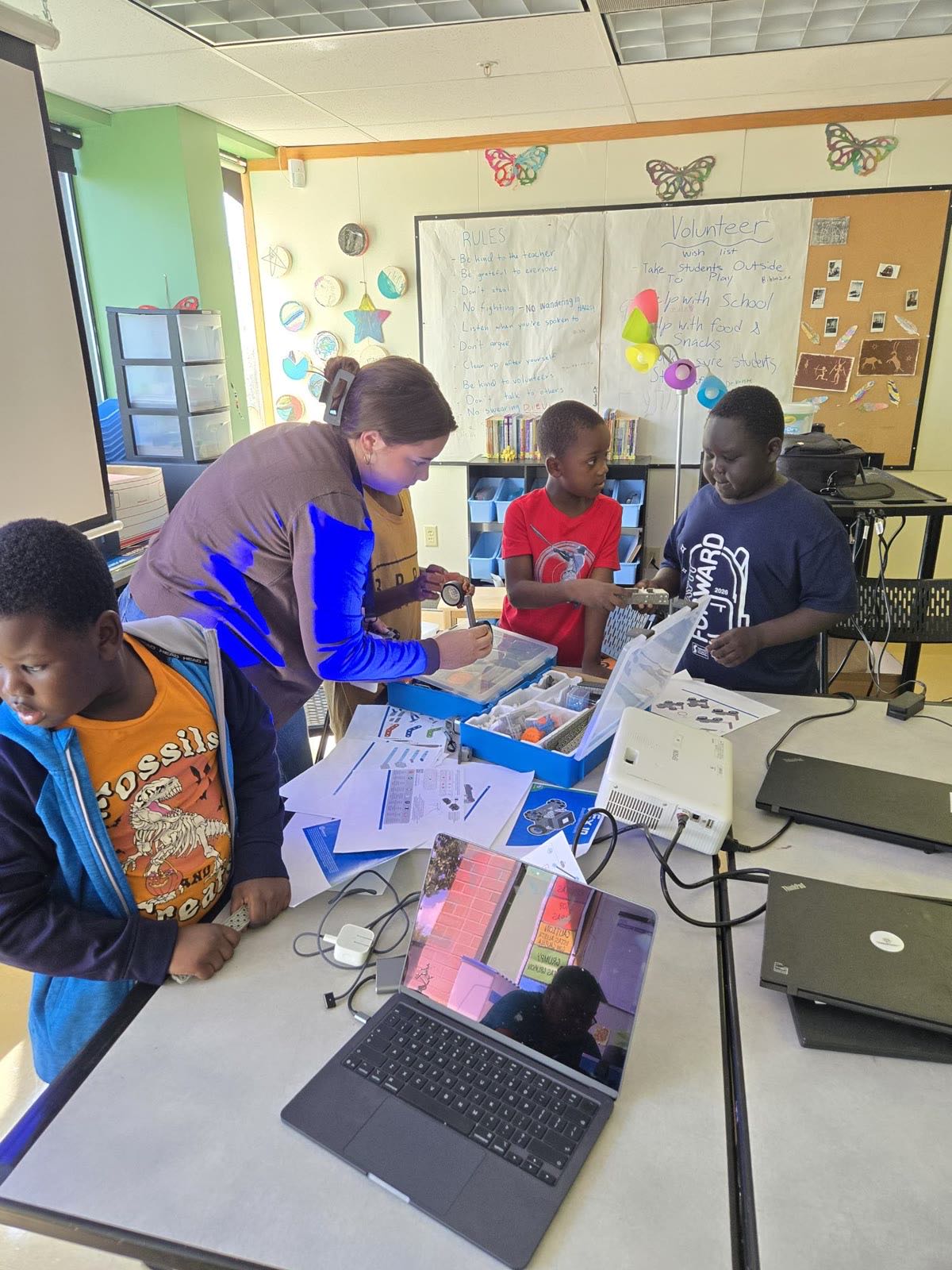 A volunteer mentor helping a team of students at their laptops