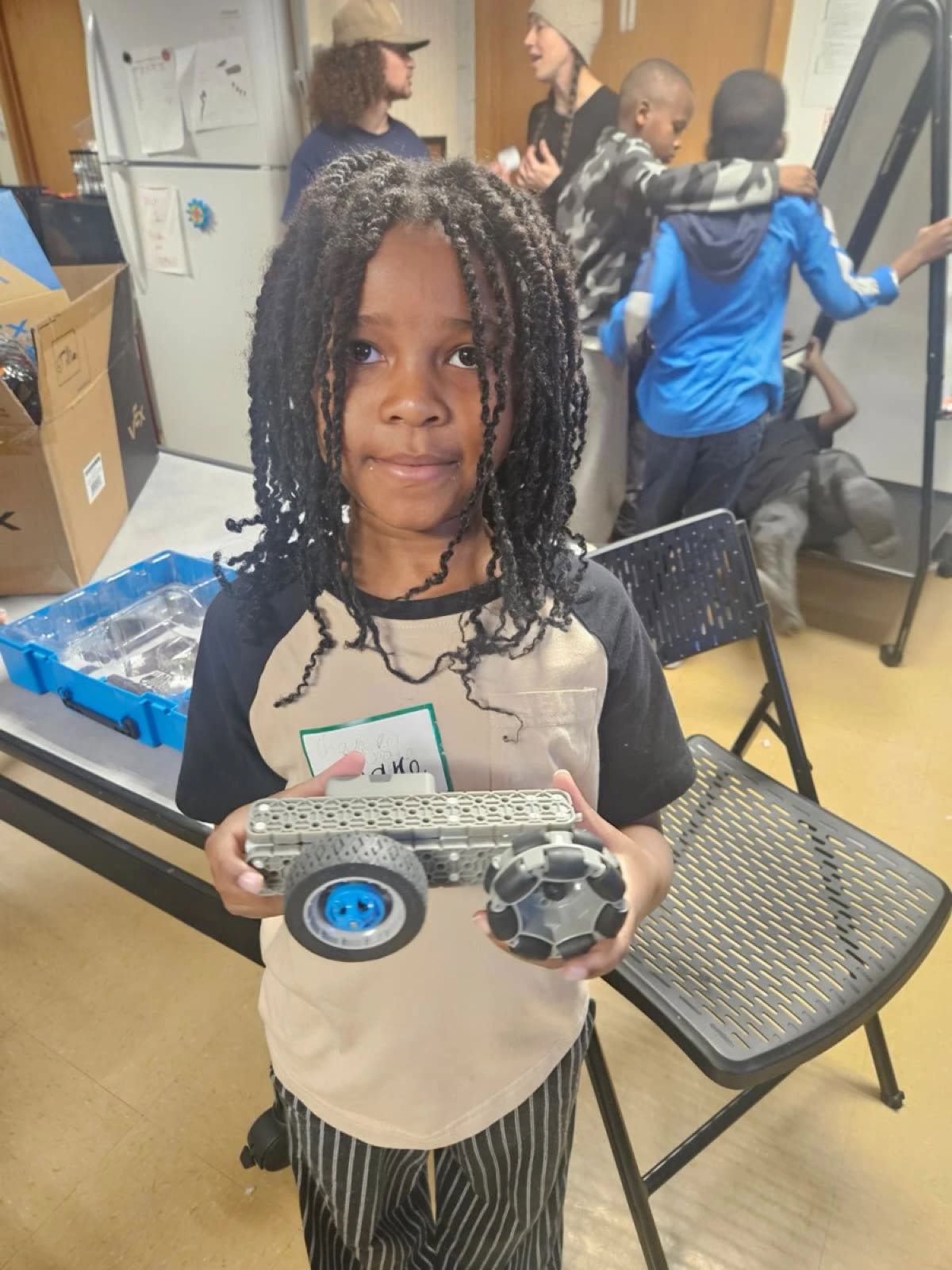 A girl in our Utah robotics class holds the VEX robot she built